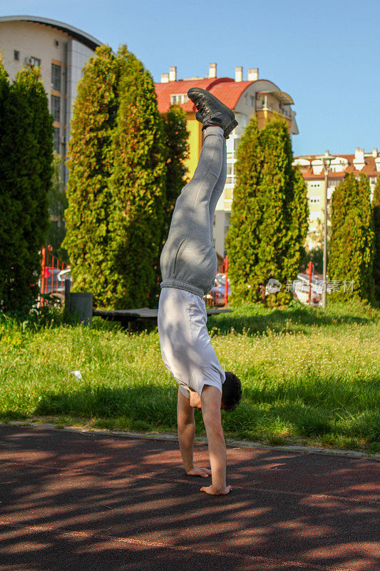 White man doing a handstand in a public park